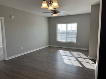A room with a ceiling fan and a window with blinds.